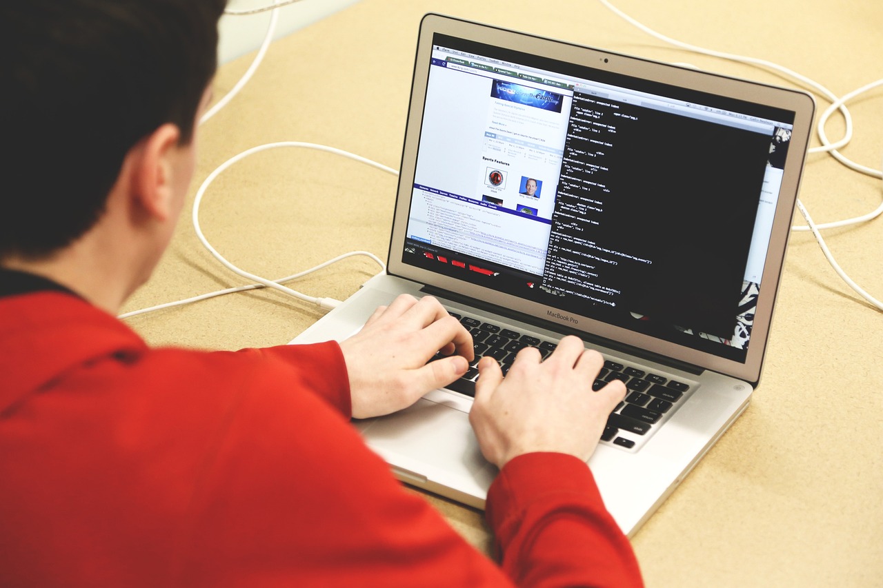 Man working at a laptop, code is visible on their laptop